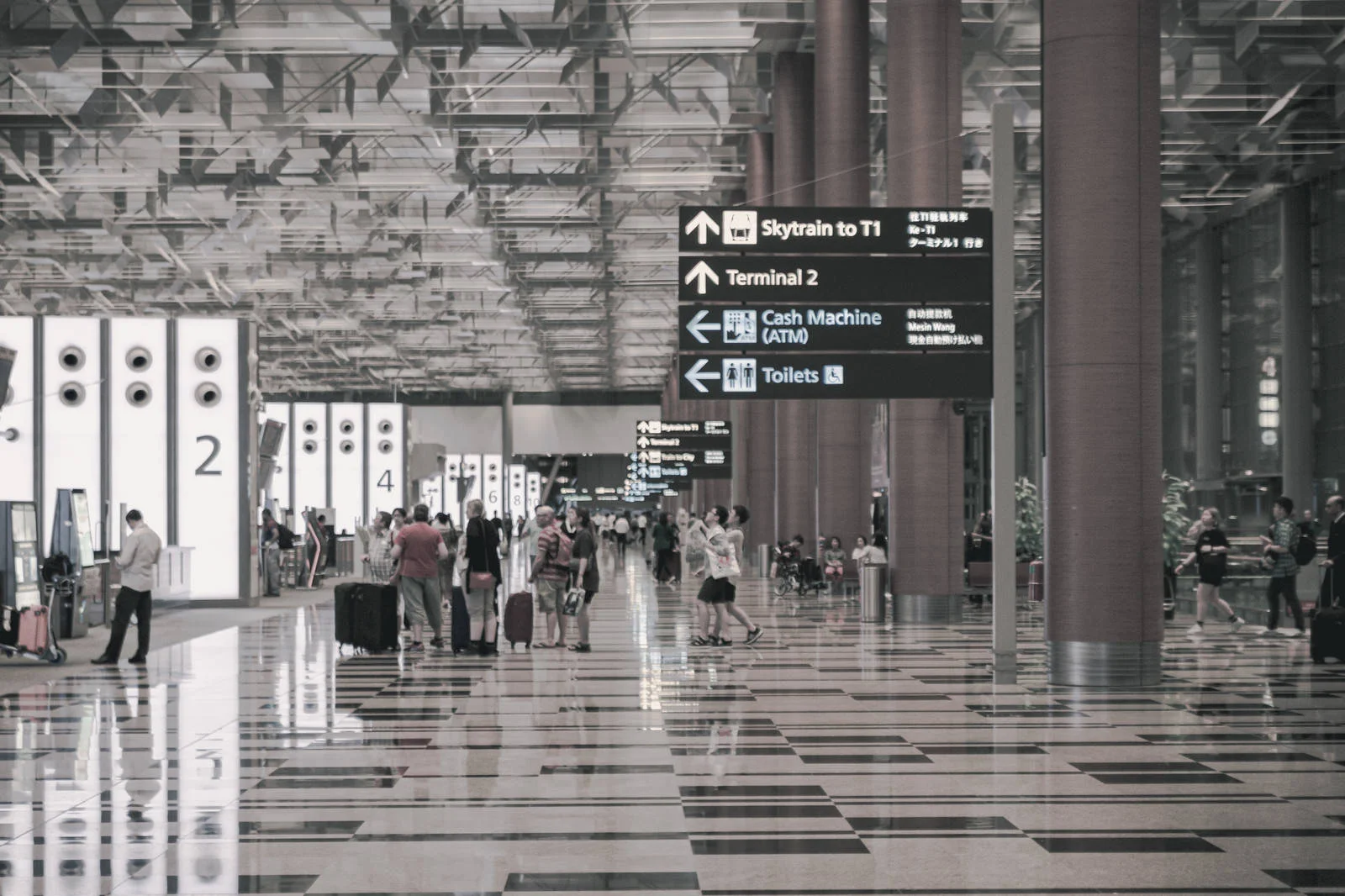 利用客が行き交う国際空港ターミナルの内部風景。進行方向を示す案内表示と広い動線が広がる空間