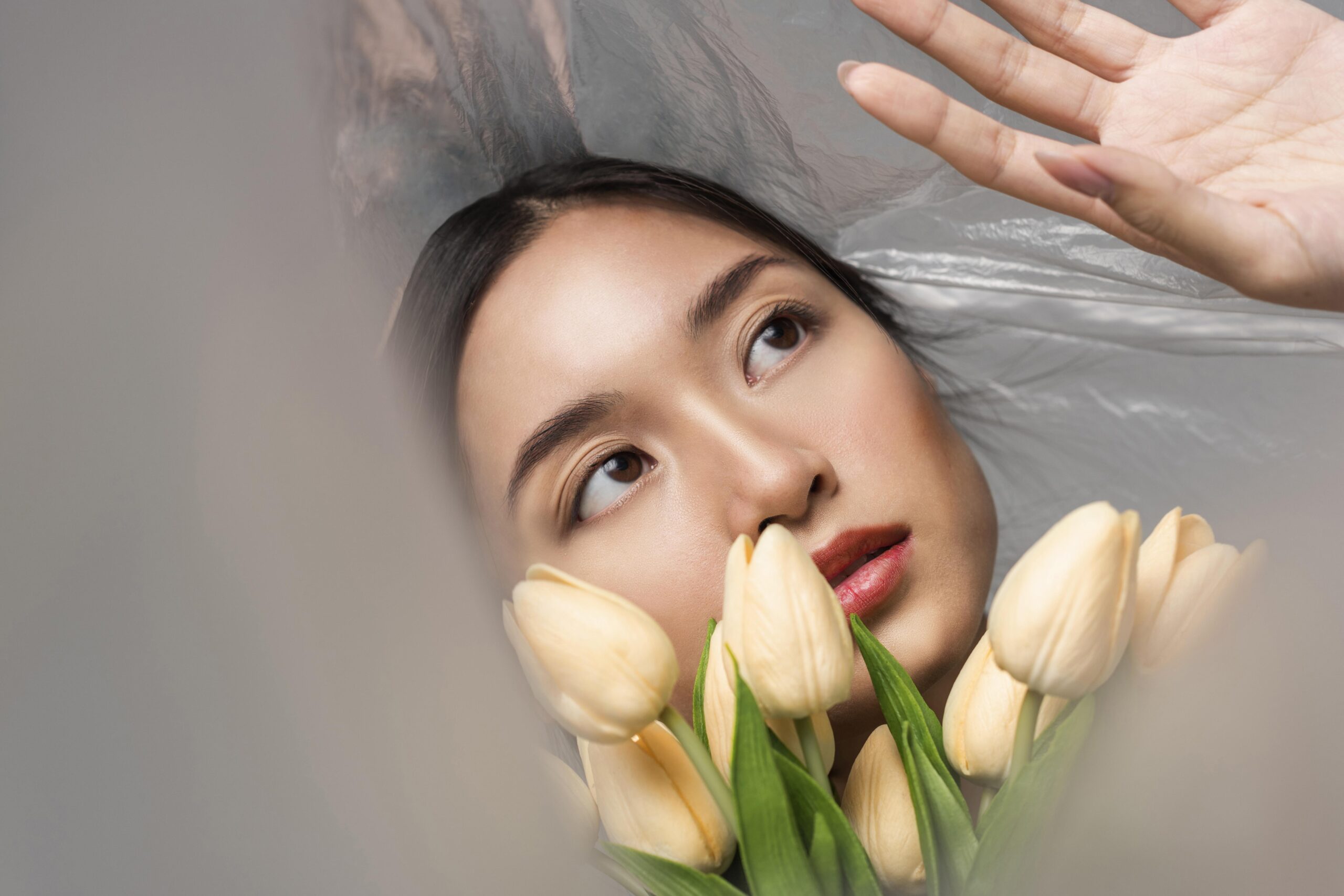 医学発想のスキンケアを象徴する、自然光の中でチューリップを手に静かに佇む東洋人女性のポートレート