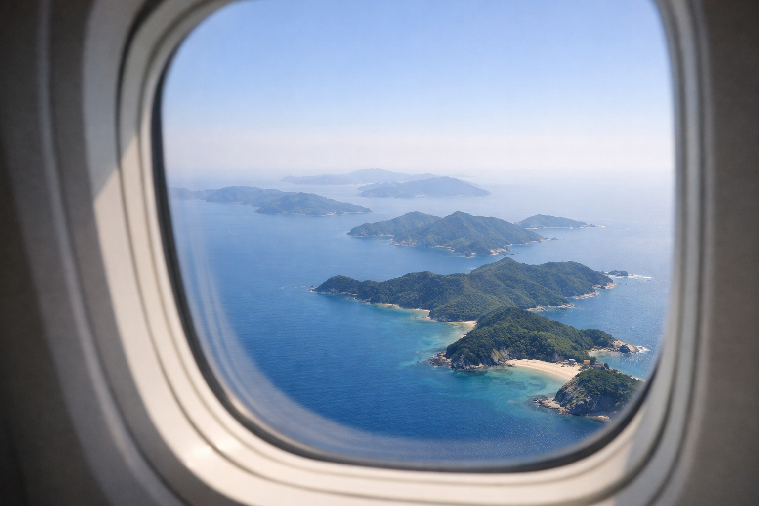 機内の窓越しに、青い海に浮かぶ五島列島の島影を静かに見下ろす景色